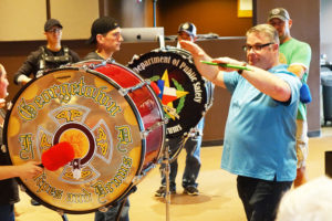 Georgetown Pipe & Drum snare drum instructor Stephen Cameron leads the blended group through a rendition of Amazing Grace .